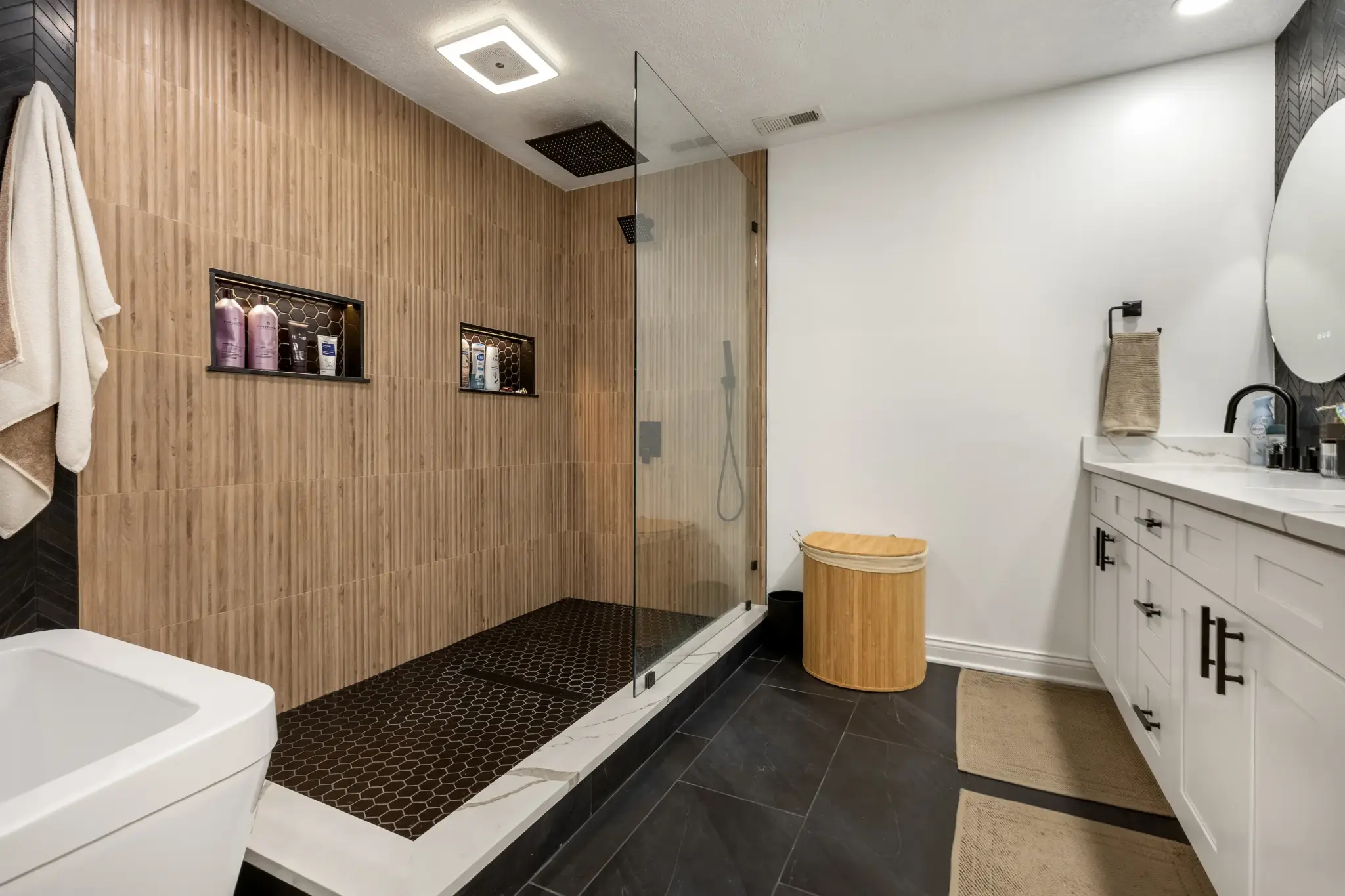 Bathroom with a wood-look tile walk-in shower and white double vanity