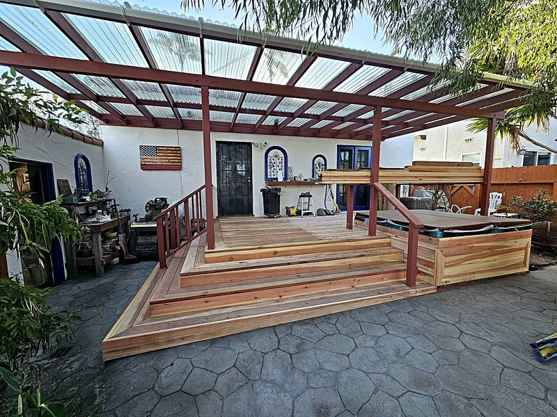 The finished wood deck and covered pergola from the stone patio, with the built-in hot tub at the right