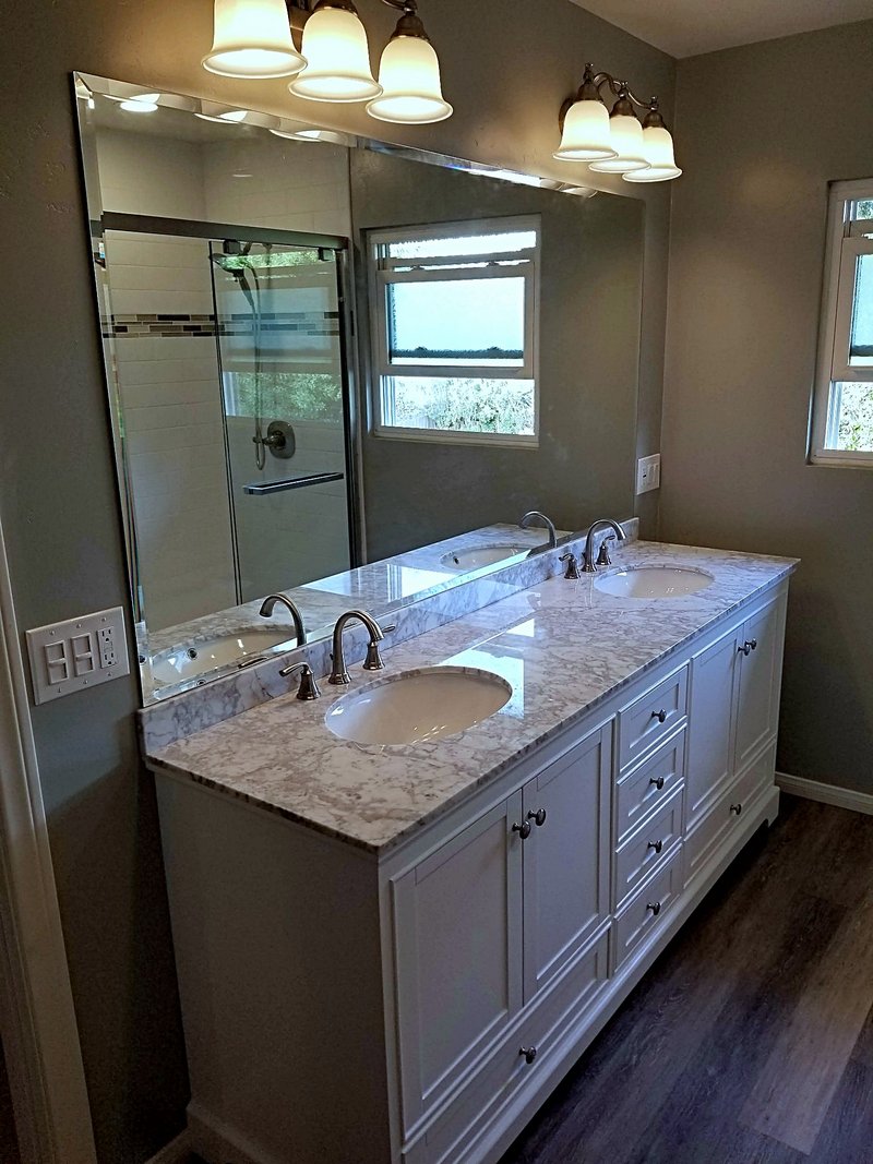 Second view of the same bathroom: a white double vanity with marble countertops and a full-width mirror reflecting the subway tile shower