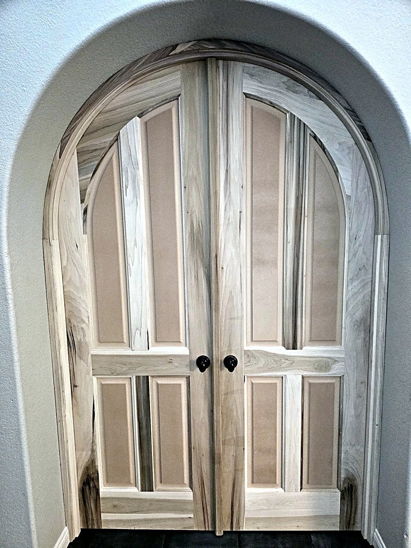New arched double doors installed in raw unfinished wood, before painting