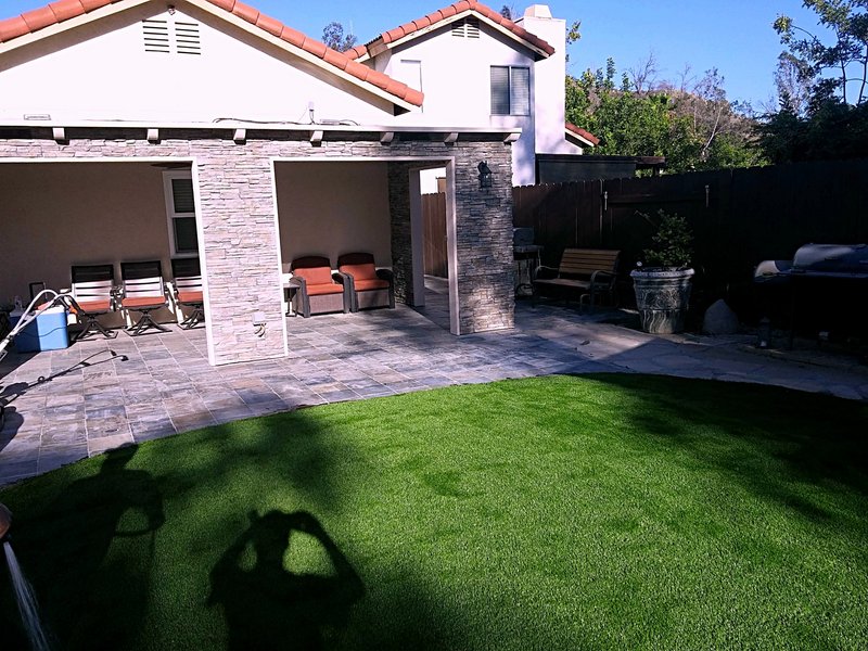 Second view of the backyard project: the stone-clad patio cover and slate patio from the side yard, with the turf lawn in front