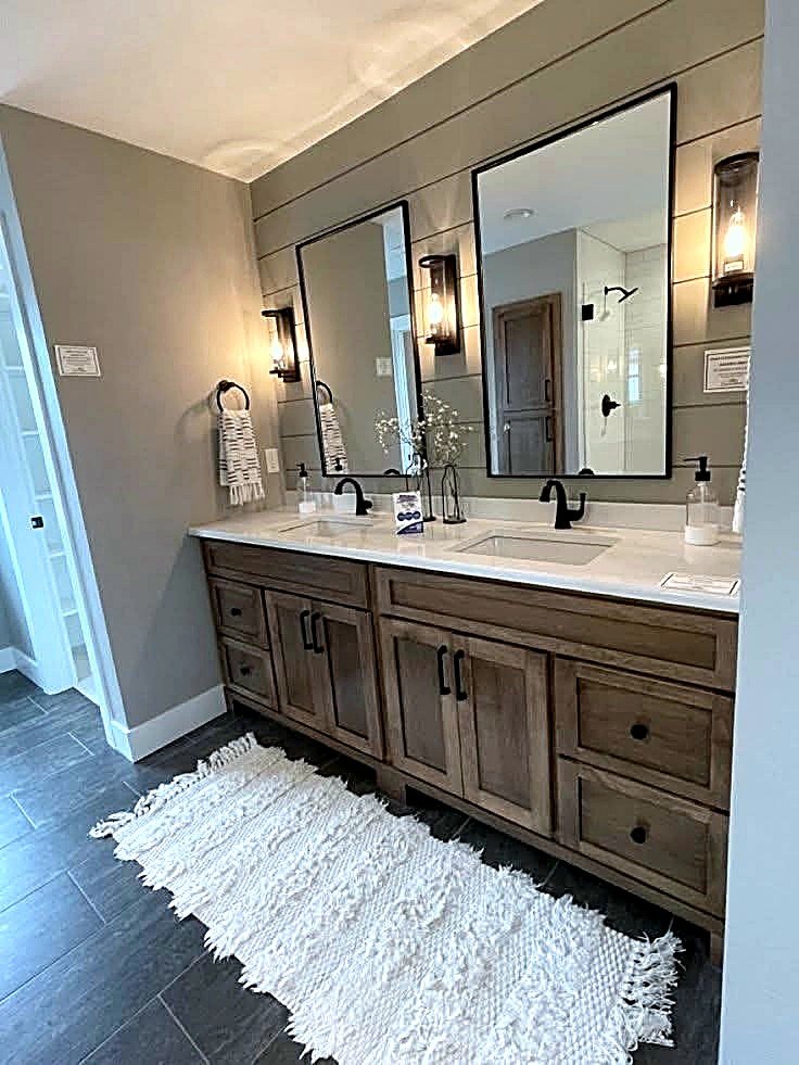 Bathroom with a rustic natural wood double vanity, black-framed mirrors, cage-style sconces, and a sage shiplap accent wall