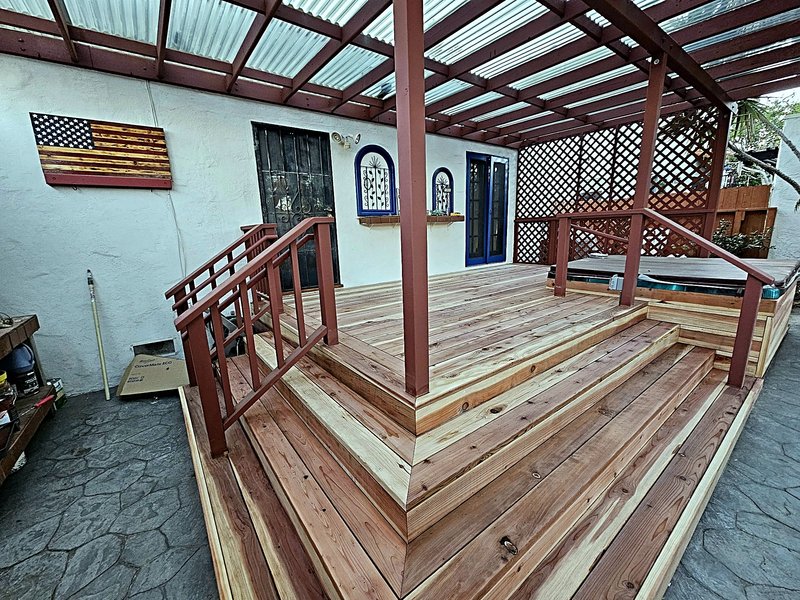 Closer view of the tiered cedar deck boards, steps, and the lattice privacy screen beside the hot tub