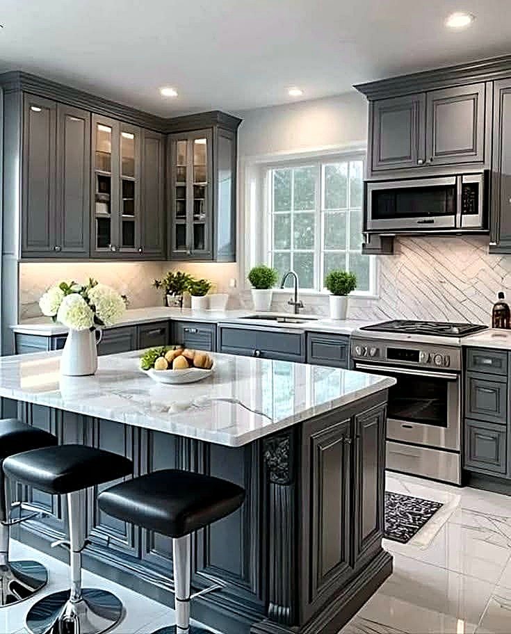 Dark gray shaker kitchen with a marble-look island with seating, glass-front upper cabinets, chevron tile backsplash, and stainless appliances